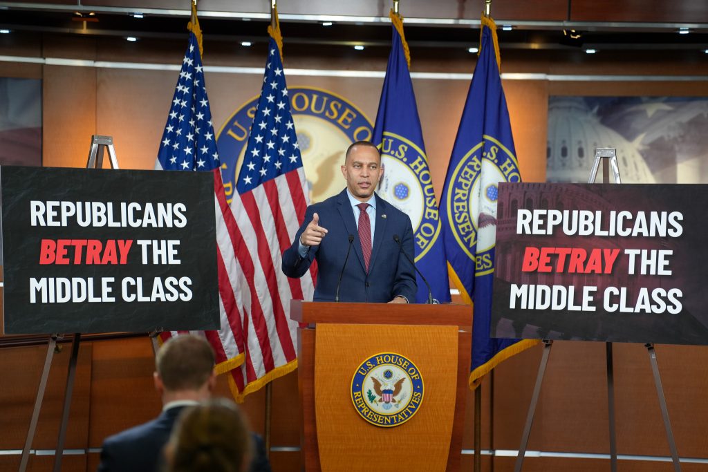 Leader Jeffries speaking at his Weekly Press Conference with posters on his left and right reading "Republicans Betray the Middle Class"