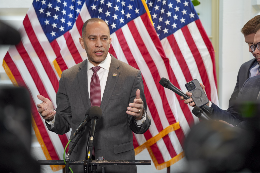 Leader Jeffries speaking at press conference in front of three American flags